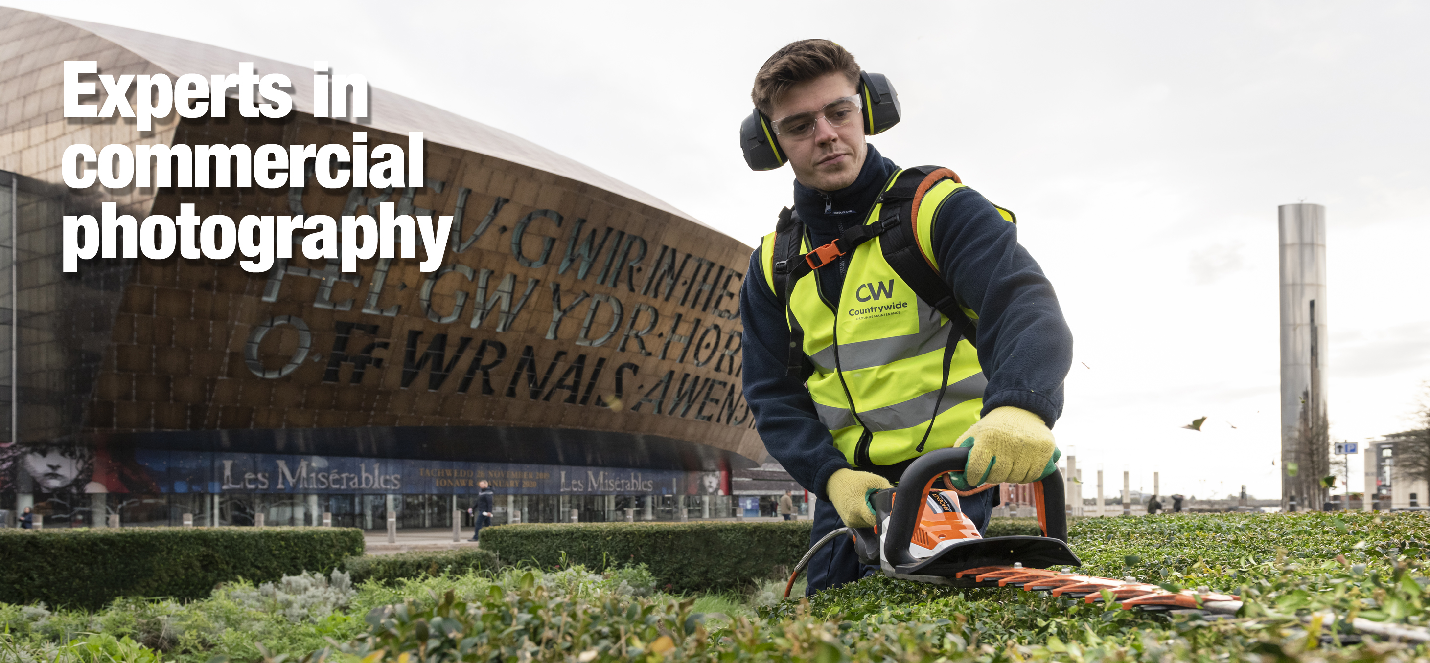 A man in a high-vis jacket trimming a hedge